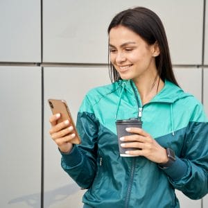 Happy woman in sportswear using mobile phone