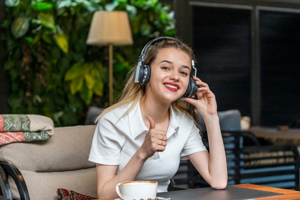 Sweet girl wears headphones and gesture thumb up