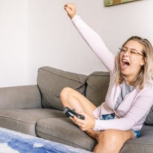Astonished woman playing videogame on sofa