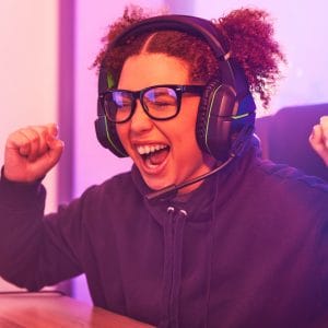 Winner, wow or woman gamer success on computer with microphone celebrating game win and fist bump.