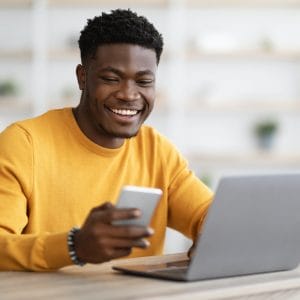 Young black man entrepreneur working on laptop and using cellphone