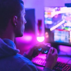 Young gamer playing online video games while streaming on social media